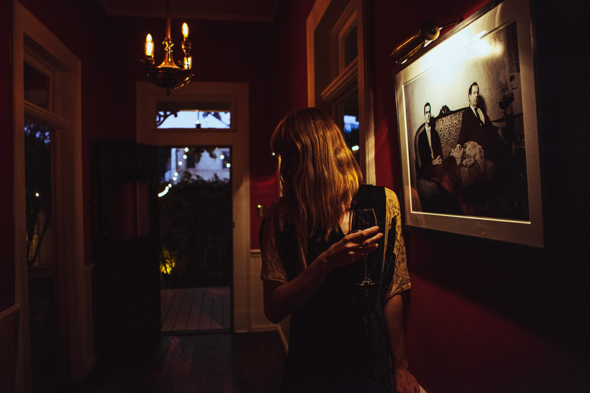 A guest enjoying wine beside the eclectic portrait collection at Justine’s Secret House
